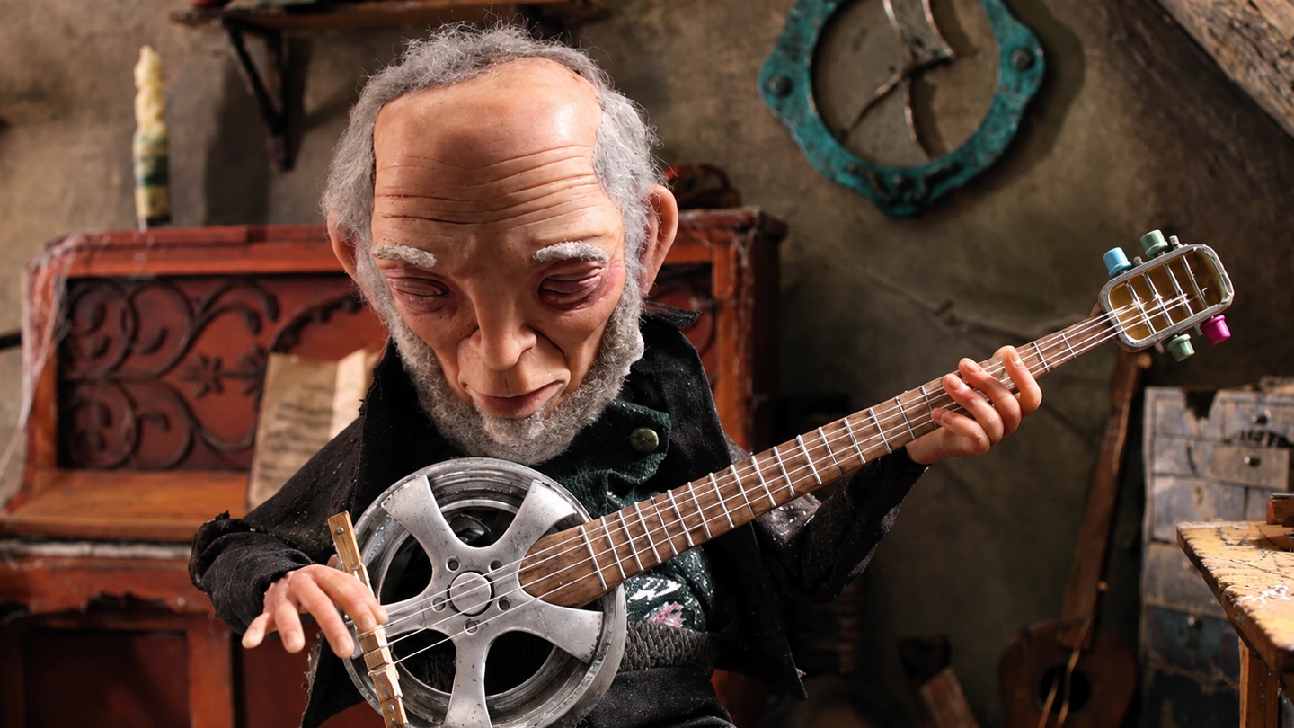 Personaje de stop motion tocando un instrumento artesanal.