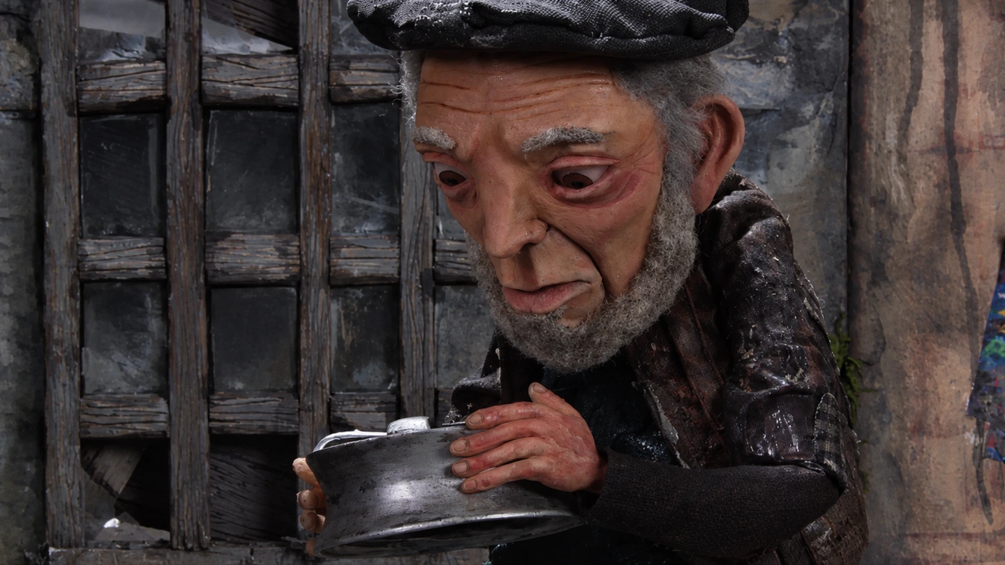 Primer plano de un personaje de stop motion sosteniendo una pieza metálica.